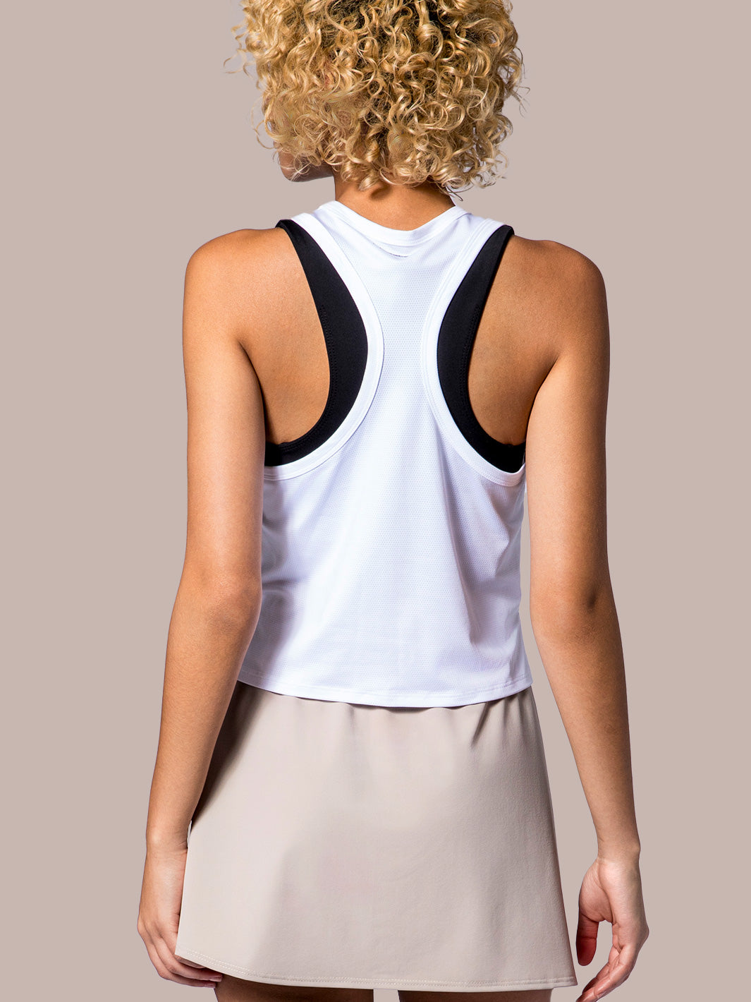 Rear view of a white PB5Star Cropped Racer Back Tank, paired with a the Lightweight Skirt in soft clay, highlighting the sporty back design.
WHT-10025