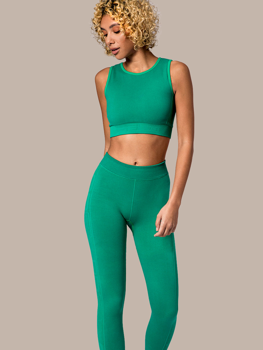 Woman modeling the PB5star 7/8 Seamless Compression Leggings in jade, paired with a coordinated Compression Knit Sports Bra. These high-waisted leggings are designed for the active pickleball player, with a focus on comfort and performance. 