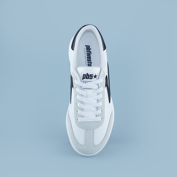 Top view of PB5STAR Cosmic sneaker in white and black with grey toe detail and logo on tongue, shown on light blue background.