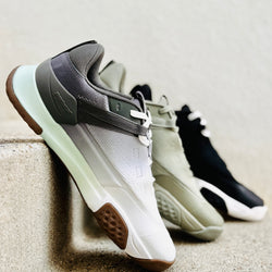 Three pairs of Court2 sneakers in different colors leaning against a light-colored wall.