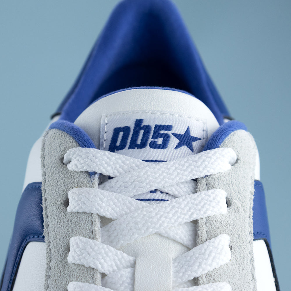 Close-up of a blue and white sneaker with 'pb5' branding on a light gray background