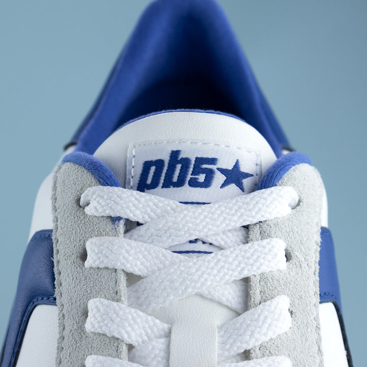 Close-up of a blue and white sneaker with 'pb5' branding on a light gray background