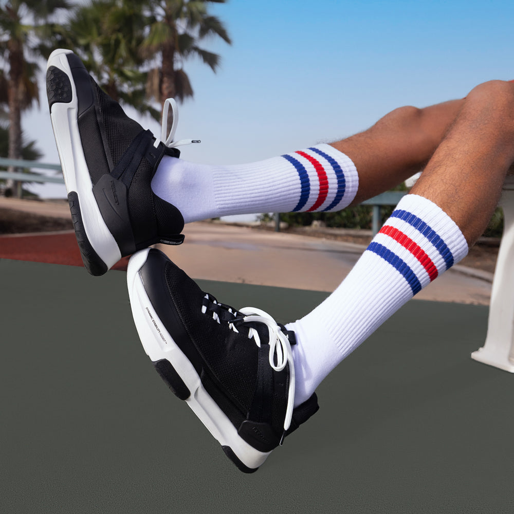 Lifestyle image highlighting black PB5 COURT2 court shoes worn on an outdoor court.