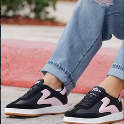 Lifestyle close-up of black-and-powder pink PB5 sneakers on pavement with rolled-up denim.