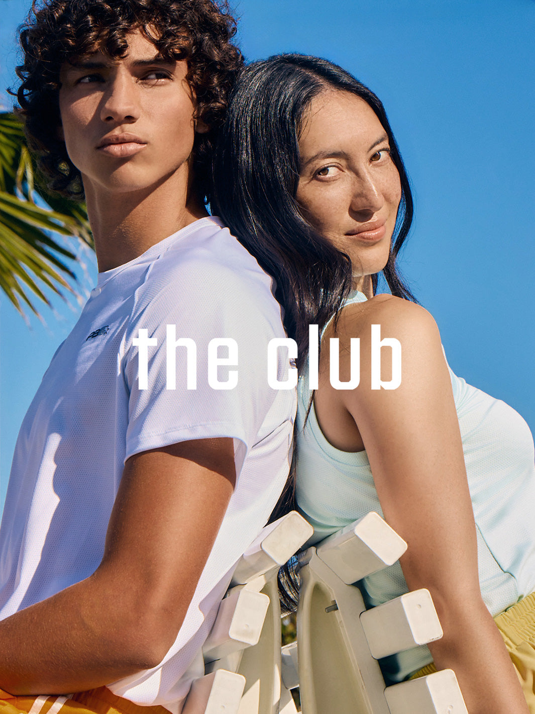Outdoor fashion shot of two people posing back-to-back; ‘the club’ headline across the center