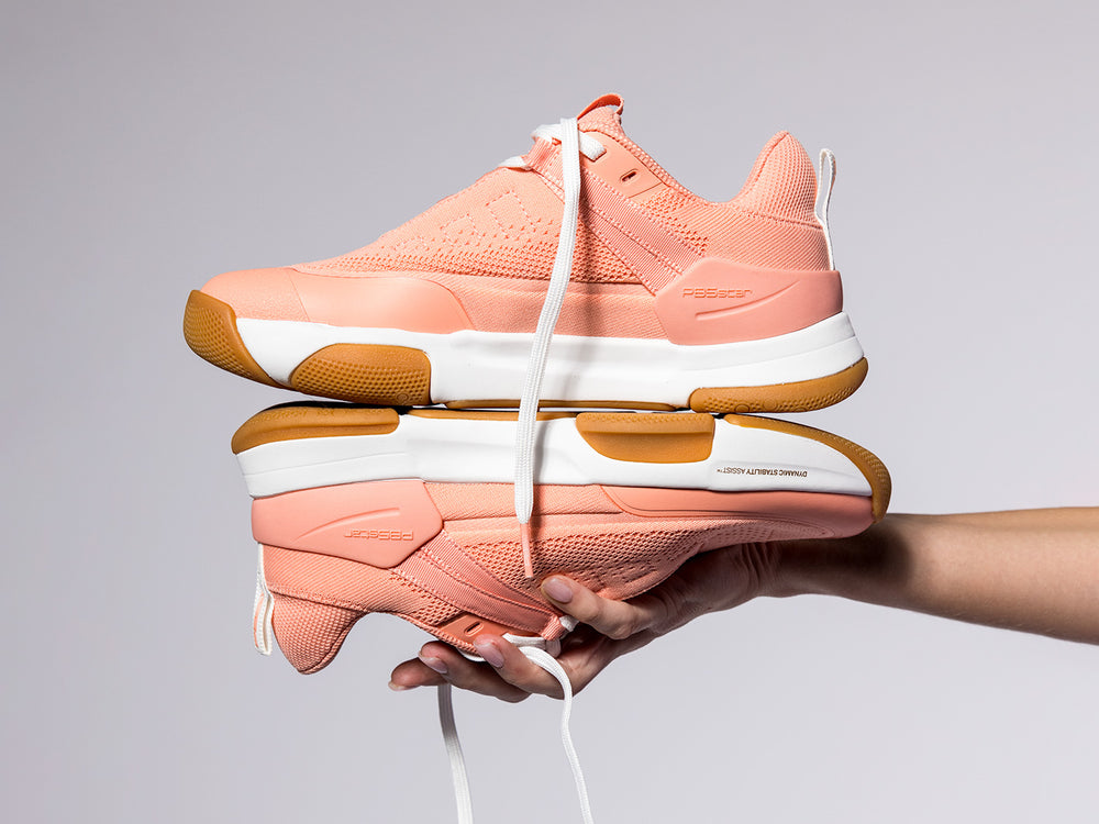 Women’s Court2 pickleball shoes in peach with gum soles and dynamic stability assist, displayed in hand