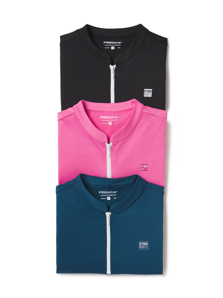 Group of women’s zip tee shirts in black, pink, and astral blue neatly folded on white background
