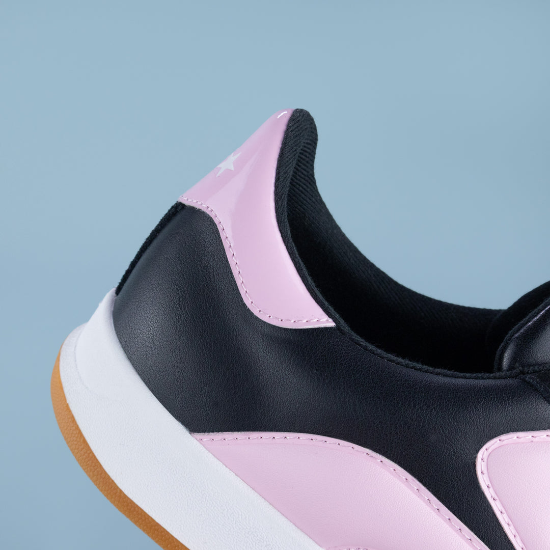 Close-up of a black, pink, and white sneaker on a light blue background