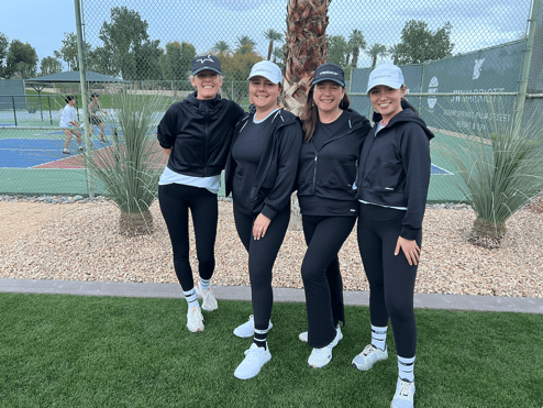 Four women wearing PB5star next to Pickleball courts