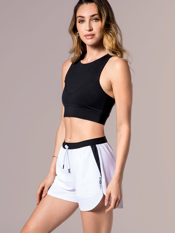 Model in PB5star Signature Court Shorts in white and black paired with a black sports bra, exuding confidence and style on the court.